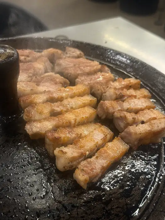 잘 구워져 노릇한 빛깔을 띠는 삼겹살과 곁들임 채소들