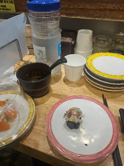 테이블 위의 초밥 접시, 컵, 물병, 젓가락 등