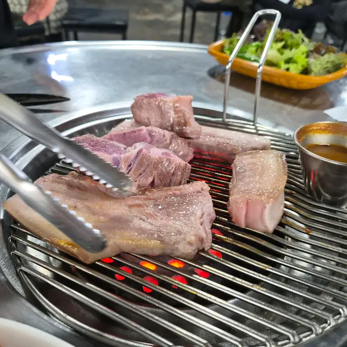 두툼하게 썰린 흑돼지 근고기가 불판 위에서 구워지고 있는 모습