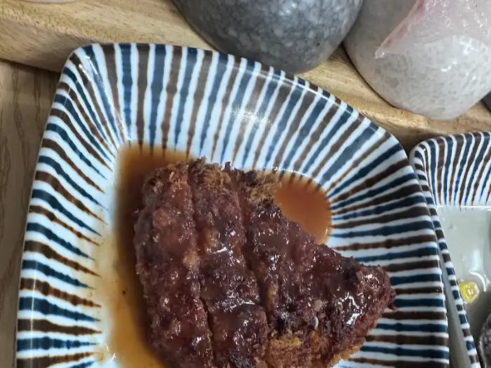 잘 익은 돈까스 조각이 접시에 담겨 소스와 함께 제공되는 모습