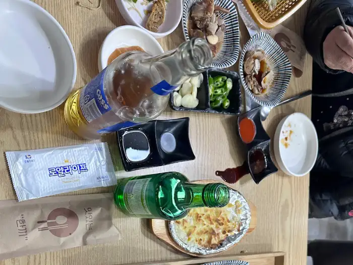 테이블 위에 놓인 소주병, 맥주병, 소스 접시, 젓가락, 냅킨 등의 모습