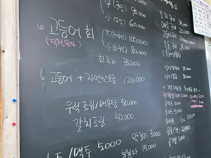 검은색 칠판에 수기로 메뉴와 가격이 적혀 있는 모습