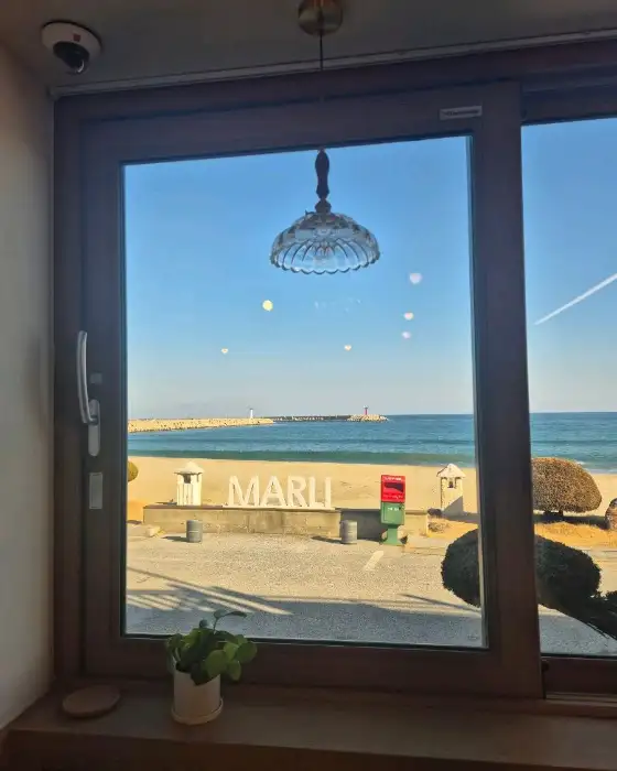 카페 창문으로 보이는 바다 풍경과 'MARLI' 간판