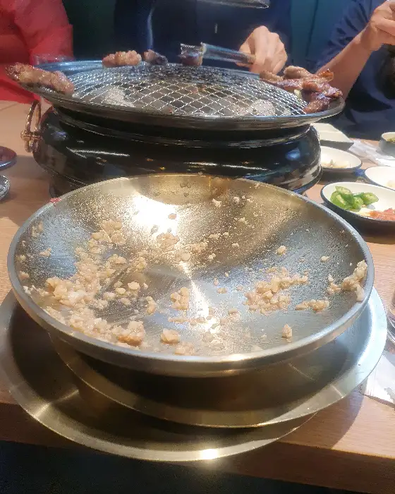 구워진 갈비살이 놓인 화로와 비빔칼국수, 된장찌개 등 다양한 메뉴가 놓인 식탁