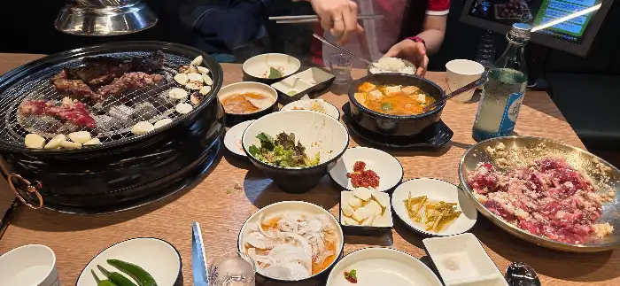 테이블에 차려진 다양한 고기와 찌개, 비빔칼국수 등 푸짐한 상차림
