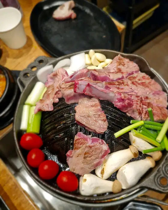 팬 위에서 구워지고 있는 양갈비와 채소들