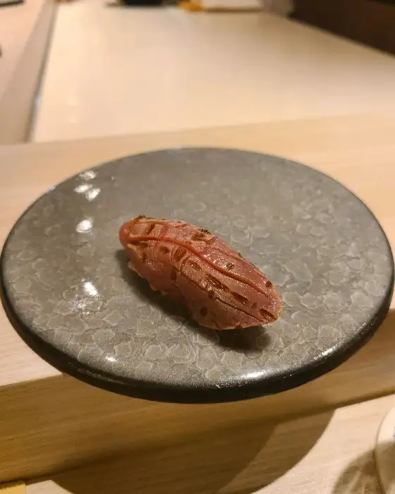 회로 덮인 스시 한 점이 회색 접시에 놓여 있다.