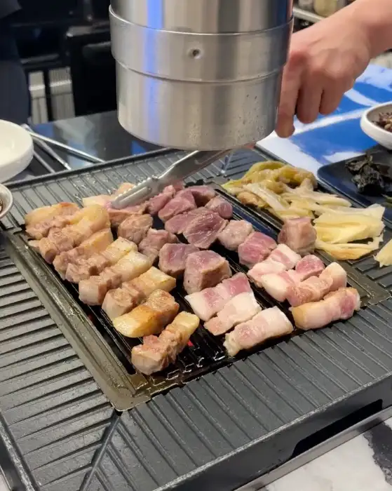 직원분이 집게로 흑돼지 고기를 뒤집으며 굽고 있는 모습