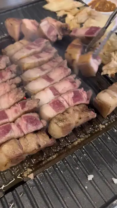 잘 익은 흑돼지 고기를 젓가락으로 집고 있는 모습