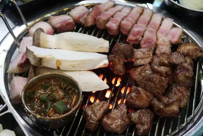그릴 위에서 구워지고 있는 삼겹살과 버섯, 쌈장