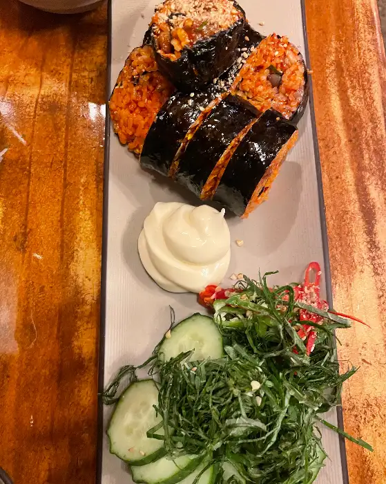알록달록한 속재료가 보이는 김밥. 밥은 붉은 빛을 띠고 있으며, 여러 가지 채소가 함께 말려 있습니다.