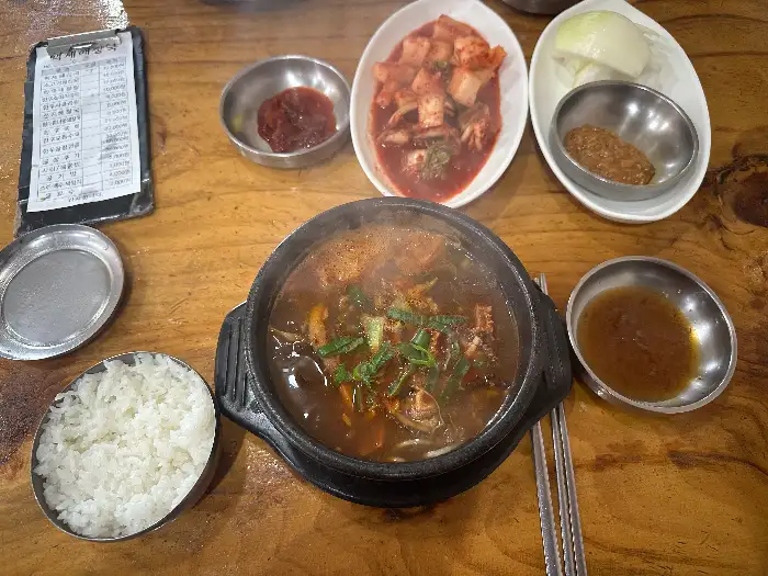 해장국, 밥, 김치, 깍두기, 소스 등이 차려진 테이블 전체 모습