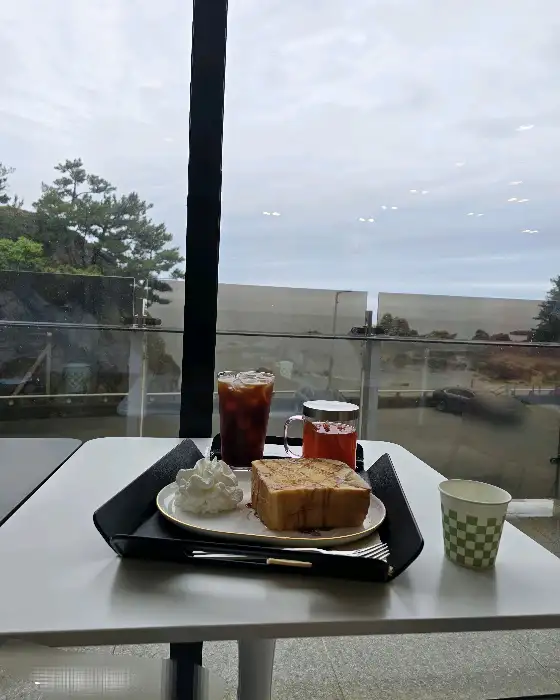 바다가 보이는 창가 테이블에 놓인 빵과 음료