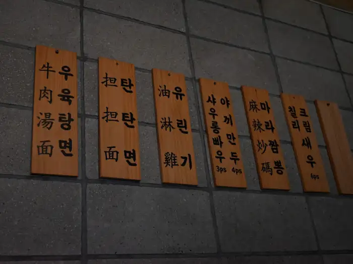 기린면방 메뉴를 보여주는 나무 간판