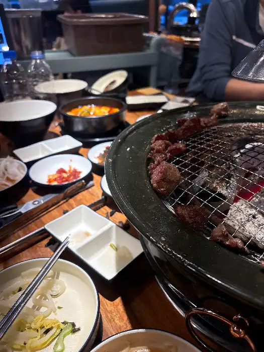 숯불 화로 위에서 익어가는 소갈비살들과 테이블 위에 놓인 밑반찬들
