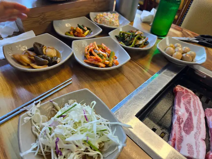 테이블 위에 차려진 다양한 밑반찬과 삼겹살