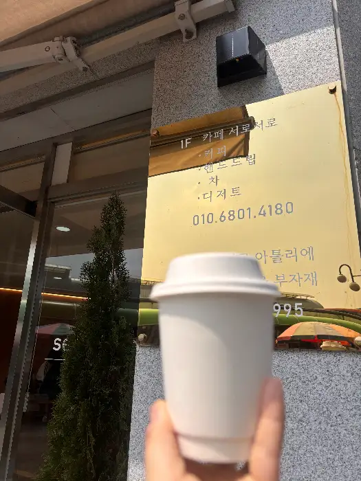 카페서로서로 간판 앞에서 컵을 들고 있는 모습