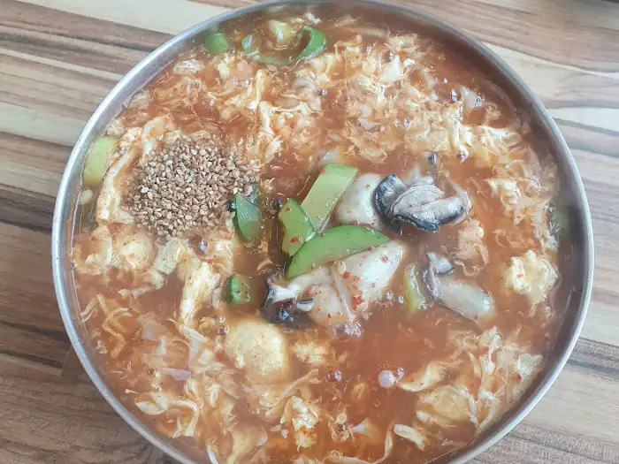 푸짐하게 담긴 굴칼국수 이미지. 굴, 버섯, 계란지단, 파 등이 보입니다.