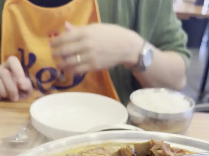 앞치마를 두른 사람이 밥과 감자탕을 준비하는 모습