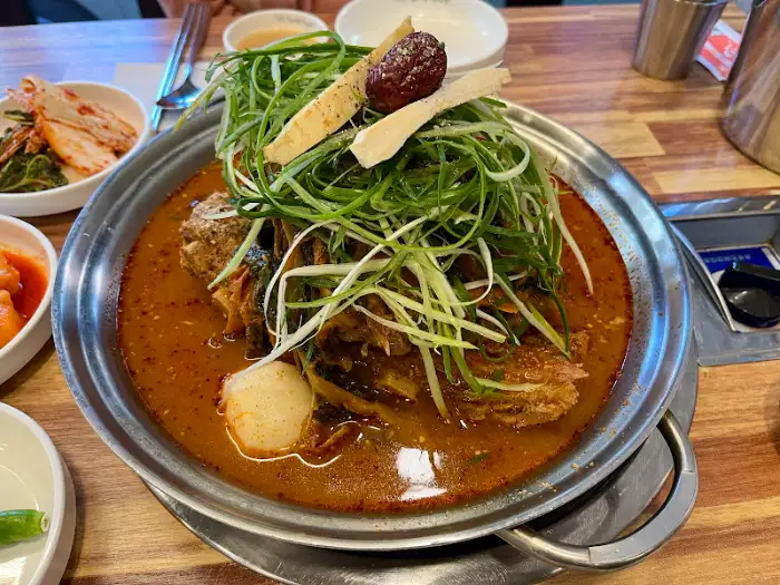김이 모락모락 나는 감자탕 냄비와 곁들임 채소