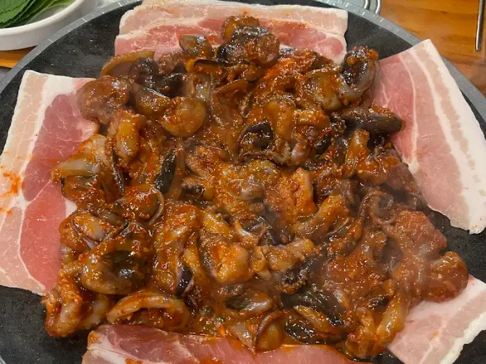 쭈꾸미와 삼겹살이 볶아진 모습, 주변에 삼겹살 조각들이 놓여있다