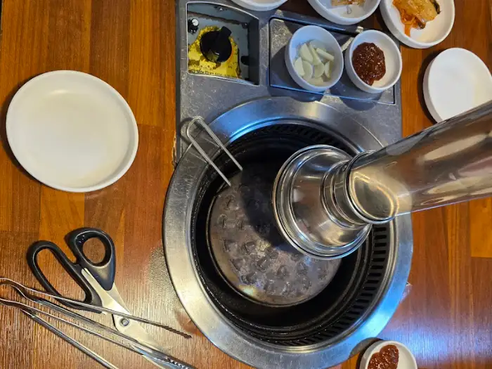 식탁 위 철제 연통과 숯불구이용 그릴, 그리고 몇 가지 반찬