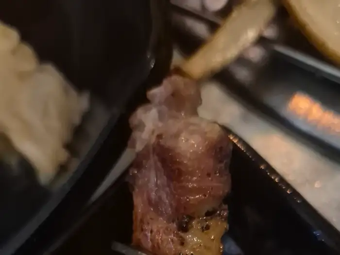 집게로 집어지는 두툼한 고기 조각, 숯불 위에서 익어가고 있다