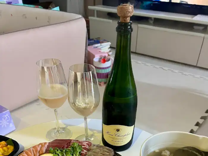 와인 병과 잔, 그리고 곁들여 먹을 수 있는 모듬회가 테이블 위에 놓여 있는 모습. 특별한 날을 더욱 특별하게 만들어 줄 로맨틱한 분위기를 연출한다.