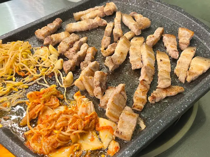 잘 익은 삼겹살과 콩나물, 김치가 함께 담긴 접시