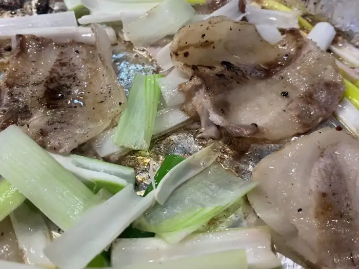 불판 위에서 구워지고 있는 냉삼겹살과 대파