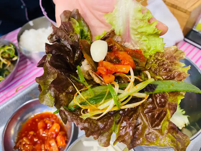 상추쌈 안에 냉삼겹살, 대파김치, 마늘 등 푸짐하게 쌈을 싼 모습