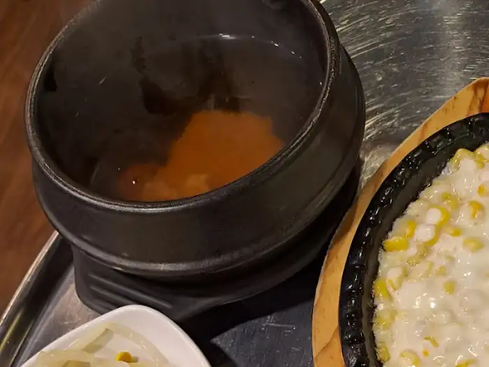앞에 놓인 뚝배기 탕과 치즈 옥수수 콘 모습