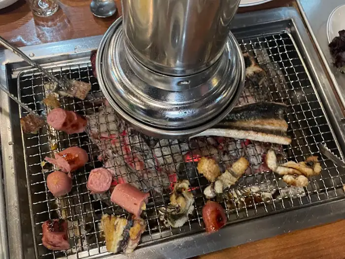 숯불 위에서 구워지는 장어와 소시지