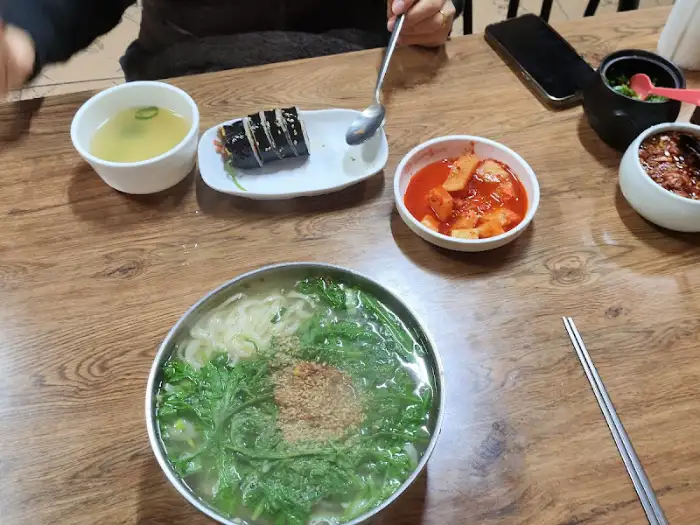 식탁에 차려진 비빔국수, 김밥, 국물, 그리고 반찬들