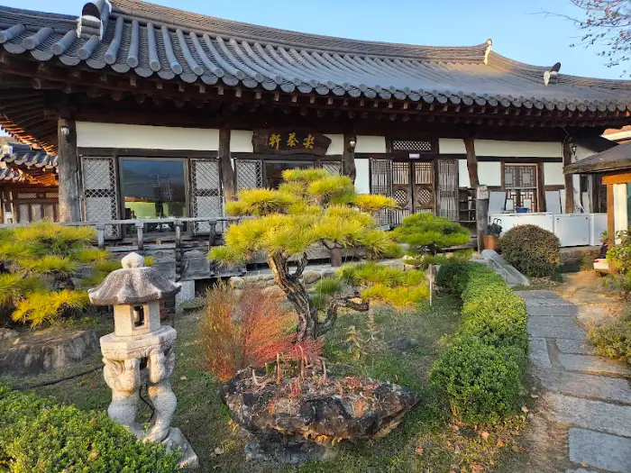 한국 전통 건축물의 정면, 잘 가꿔진 정원과 소나무 분재