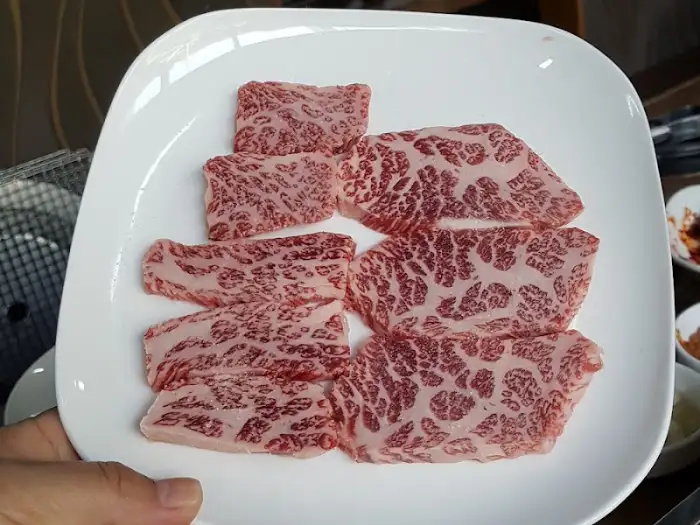 흰 접시에 담긴 마블링이 풍부한 소고기 조각들