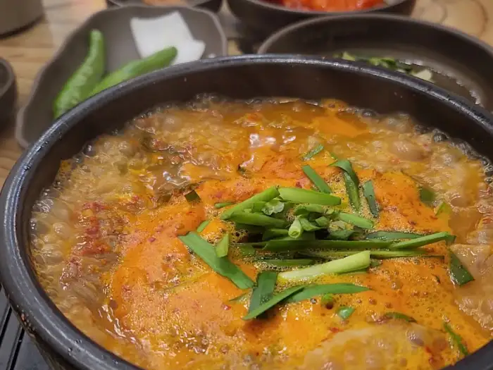 보글보글 끓고 있는 얼큰 순대국의 모습. 국물 위로 푸릇한 파가 얹어져 있다.
