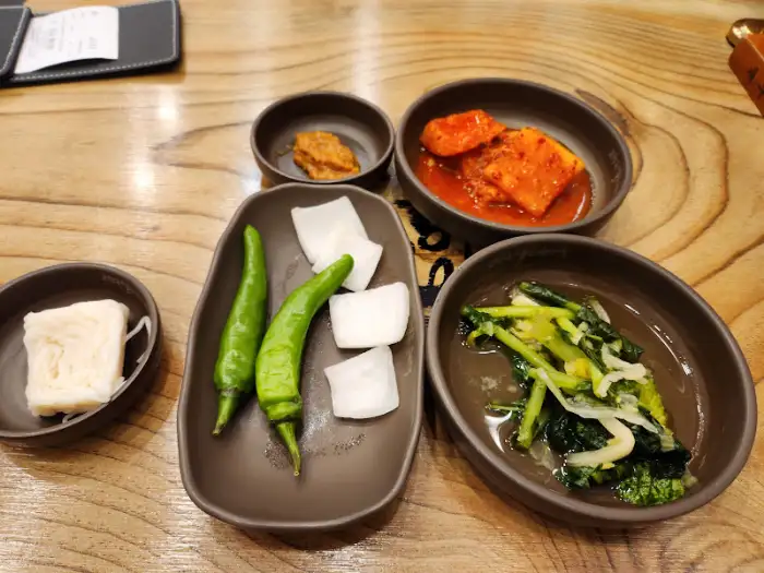 테이블에 차려진 기본 찬들. 석박지, 열무김치, 청양고추, 쌈장, 소면 등이 보인다.