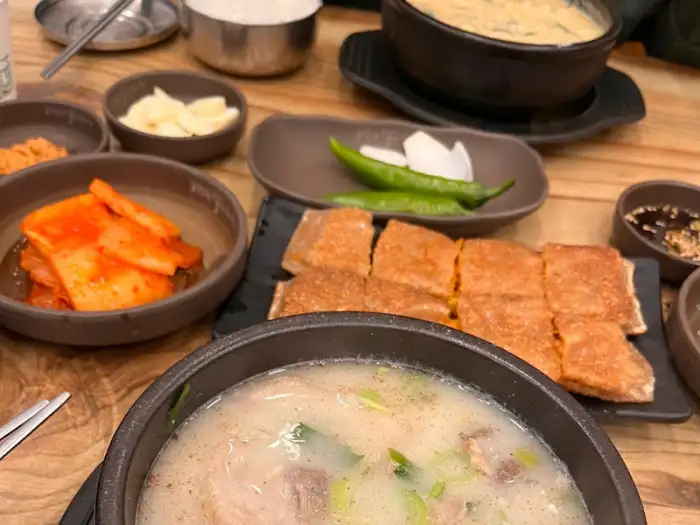 식탁에 놓인 여러 가지 음식들. 순대국, 메밀전병, 김치 등이 보인다.