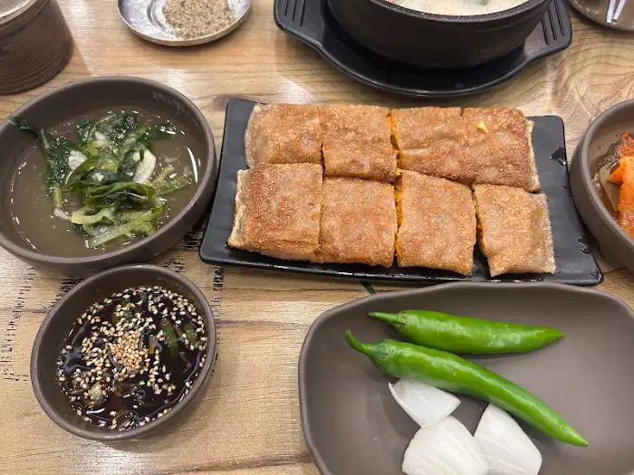 테이블 위 음식 사진. 메밀전병, 열무김치, 소스 등이 보인다.