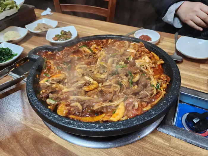 테이블 위에서 지글지글 끓고 있는 오리 양념구이