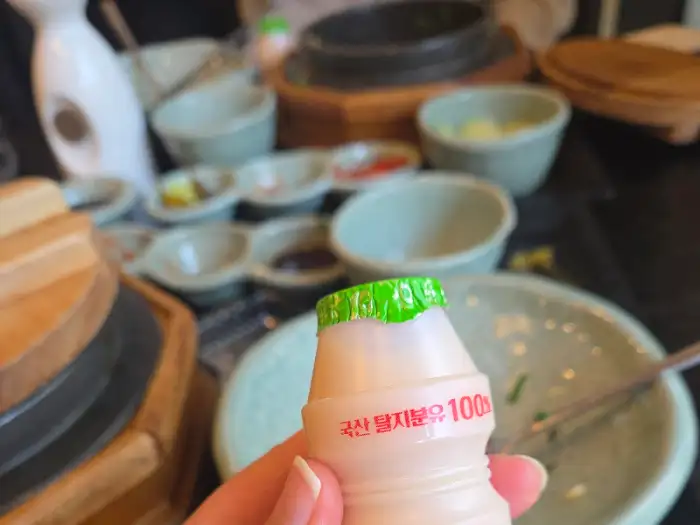 손에 들린 작은 요구르트 병, 식후 디저트로 제격입니다.