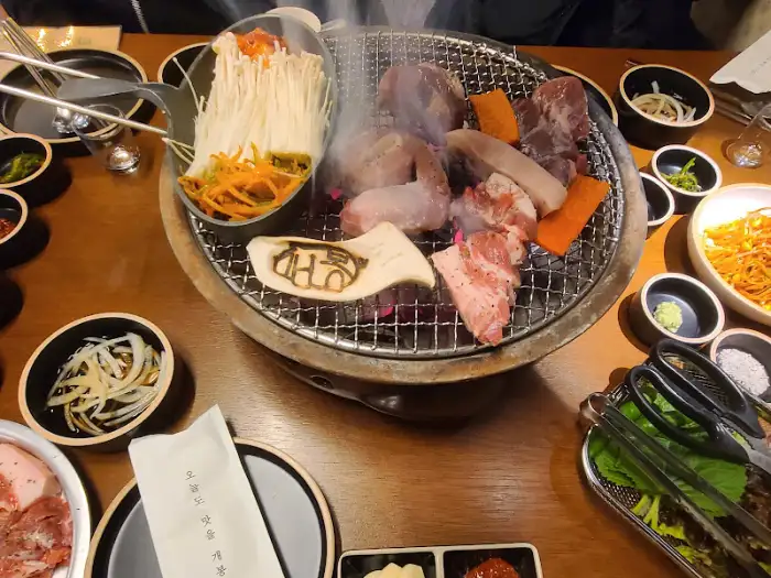 숯불 위에서 다양한 부위의 돼지고기가 익어가고 있는 모습