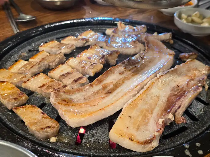 잘 익은 삼겹살 한 점을 들어 올리는 모습