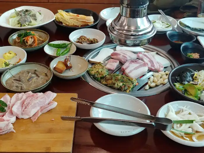 불판 위 삼겹살과 곁들임 메뉴