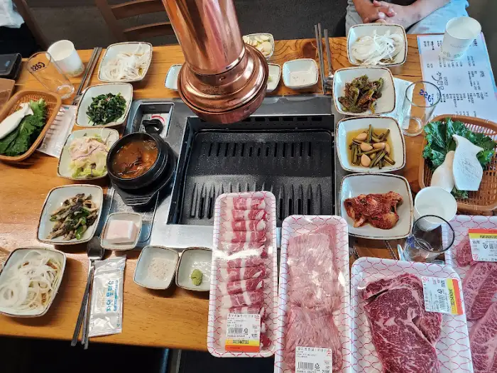 불판 위에서 구워지고 있는 고기와 다양한 밑반찬이 놓인 상차림 사진