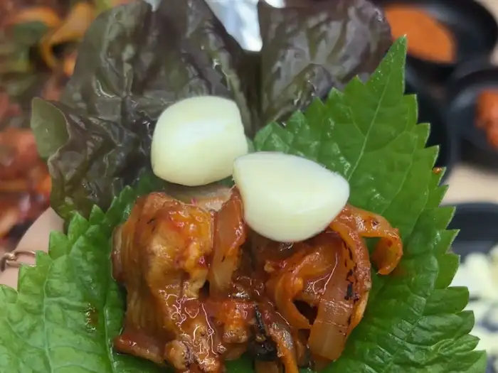 상추와 깻잎, 방아잎 위에 꼼장어와 마늘, 쌈장을 올린 쌈