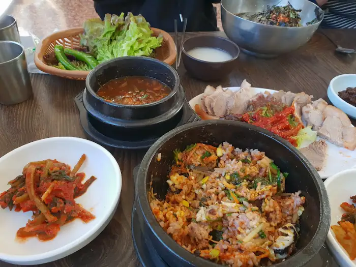 수육, 비빔밥, 그리고 여러 밑반찬이 차려진 식사 모습