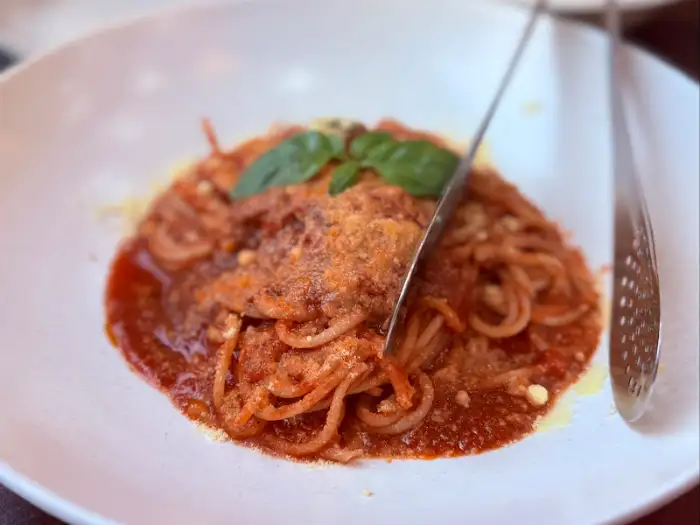 진한 토마토소스에 버무려진 스파게티 면 위에 치즈와 바질 잎이 올려진 모습