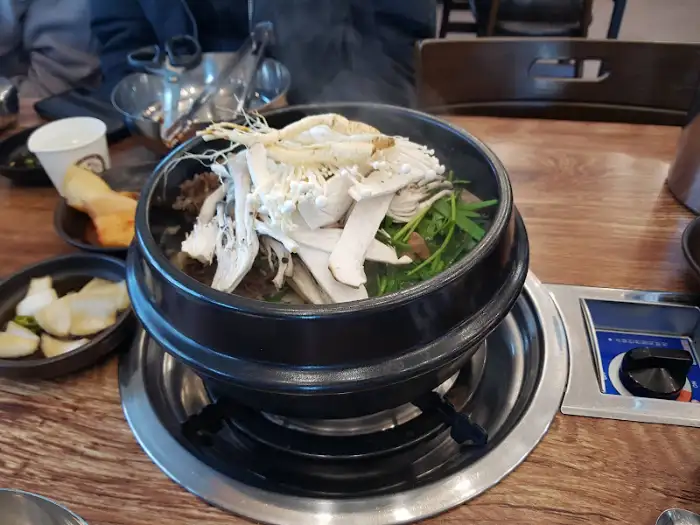 갈비탕 위에 수북이 쌓인 버섯과 미나리
